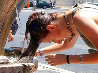 Una ragazza cerca refrigerio sotto una fontana