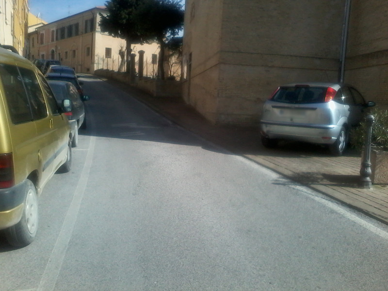 Un'automobile parcheggiata sul marciapiede della chiesa di Roncitelli