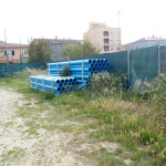 Parcheggio ex Italcementi dissestato con erba alta buche e deposito attrezzi