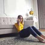 Ragazza seduta su tappeto con notebook e smartphone