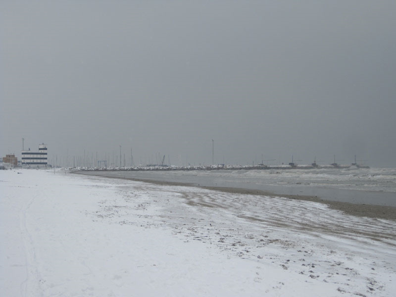 Sullo sfondo della spiaggia innevata, il porto