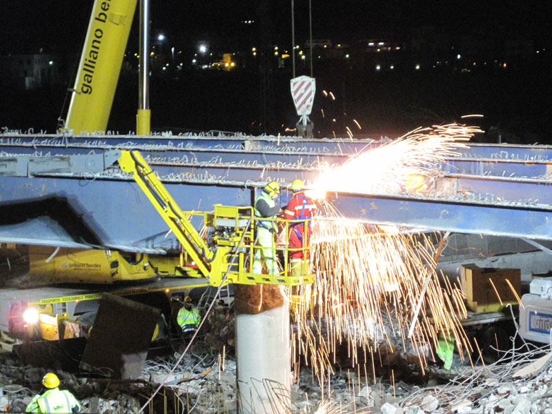 Operai staccano la struttura del ponte con la fiamma ossidrica