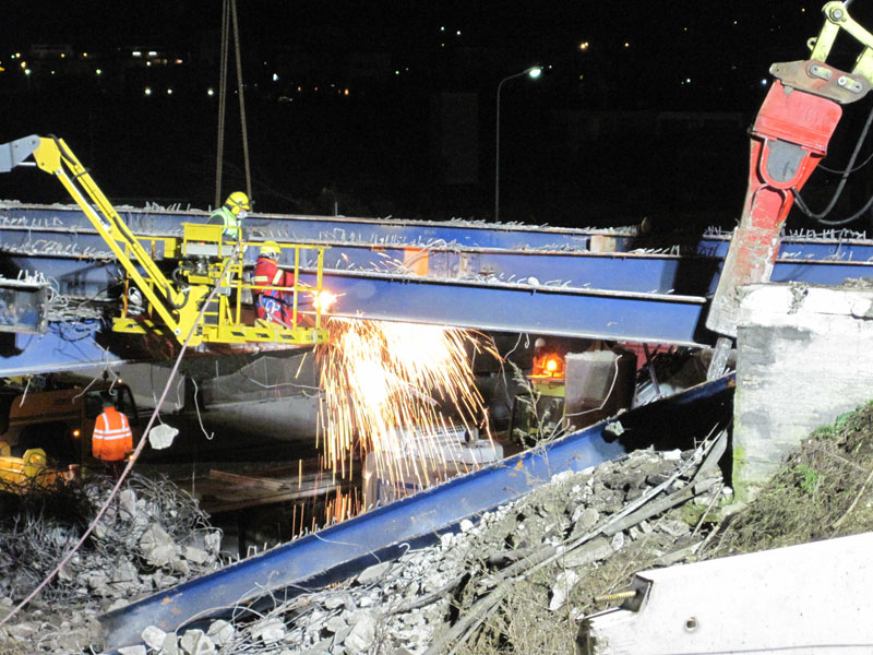 Operai staccano la struttura del ponte con la fiamma ossidrica