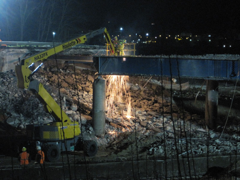 Operai staccano la struttura del ponte con la fiamma ossidrica